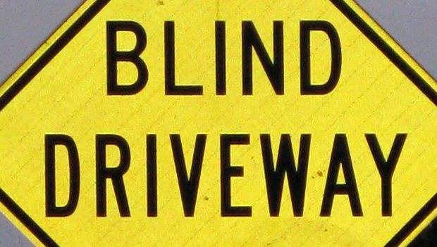 A bright yellow BLIND DRIVEWAY sign