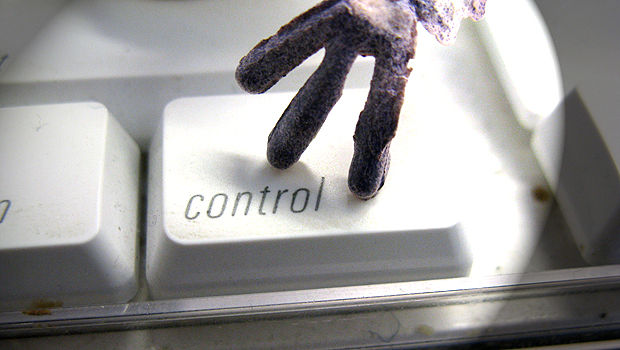 A purple toy hand hovers over the CONTROL button on a white computer keyboard.