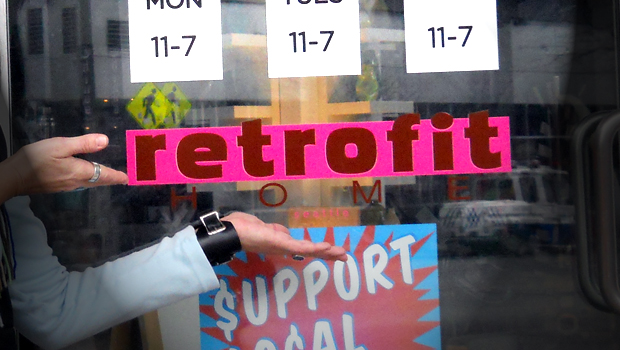 Photo of Margaret's hands pointing toward a pink store sign that reads RETROFIT
