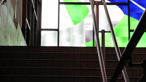 A staircase leading up to a tiled glass window (shades of blue and green).
