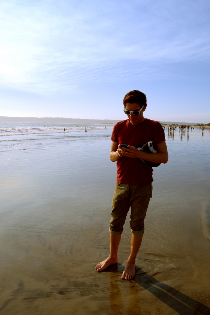 Young man on beach with cell phone