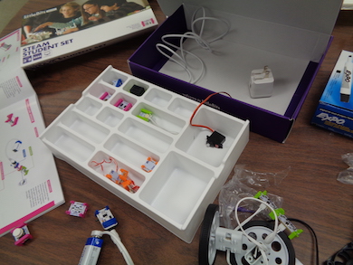 an open box of littleBits with components surrounding the box on the table