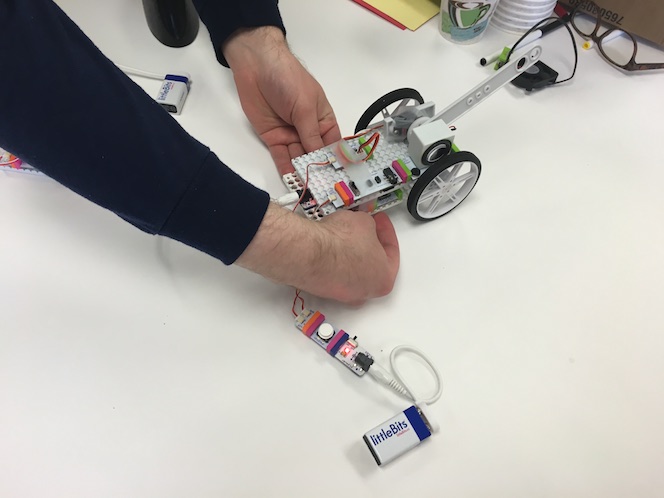 two hands are attaching components to an assemblage of littleBits