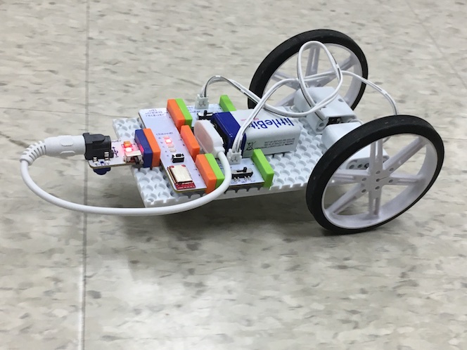 a side view of the littleBits car, with two wheels in the back and a battery and electronics attached to the base
