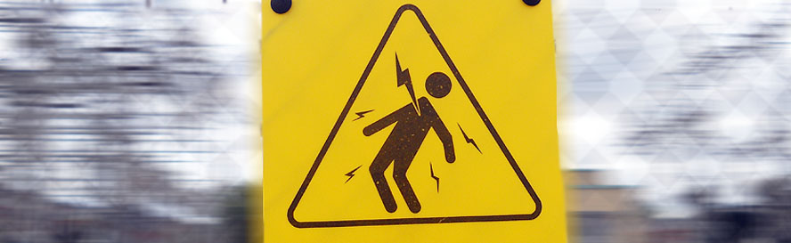 A yellow warning sign affixed to a fence. The sign features a stick figure getting struck by lightning.