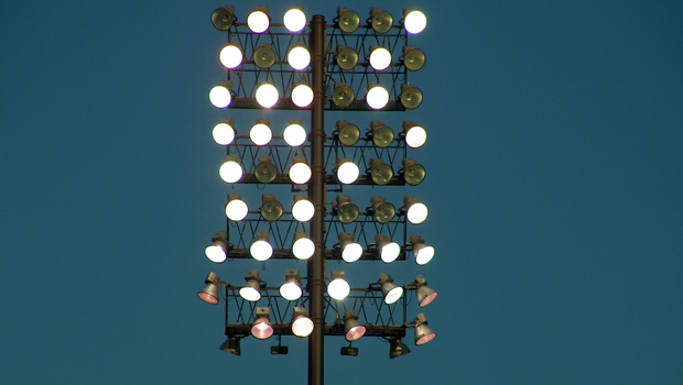 A stadium light with several lightbulbs -- half of the bulbs are lit, and half are burned out.
