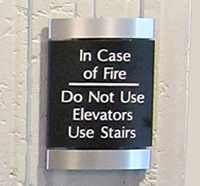 A sign mounted on the wall that reads IN CASE OF FIRE, DO NOT USE ELEVATORS. USE STAIRS.