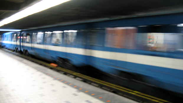 A blue subway train whizzing past the station
