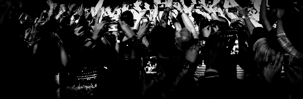 Black and white photo fans with cell phones in hand recording video, reaching out toward an unseen Bruce Springsteen, Izod Center, April 2, 2012.