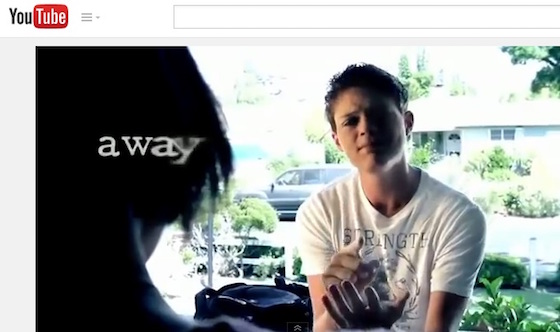 A young man is signing to a young woman. The visual text on screen shows the word “away” fading out. The letter y in “away” is more blurry than the other letters in the word.