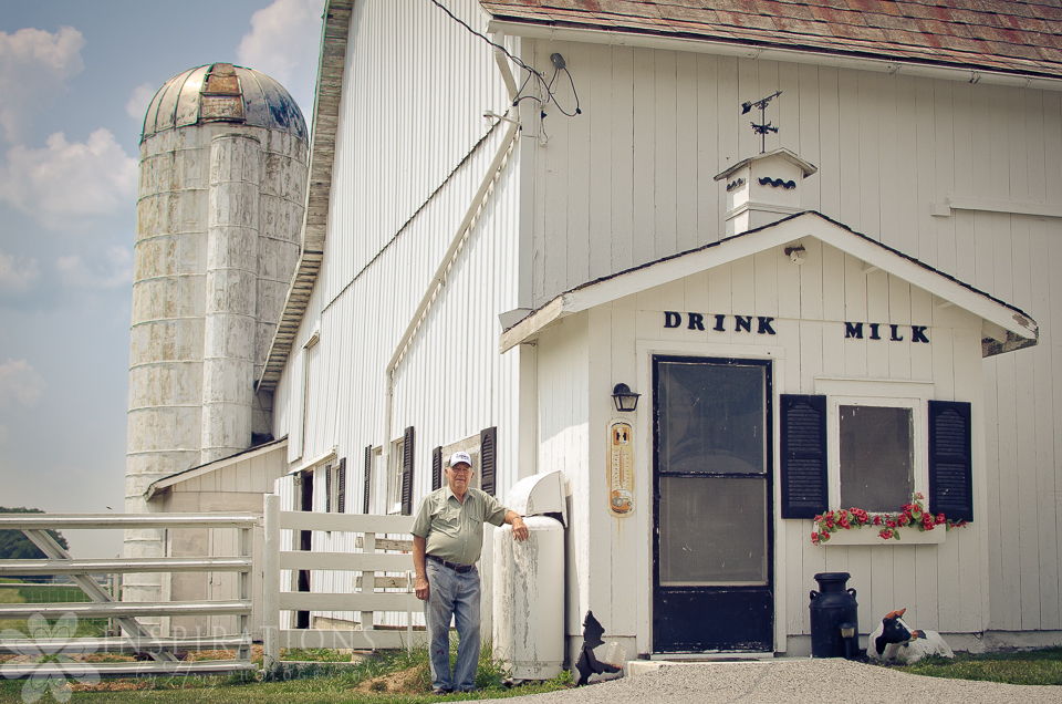 A photo of a man standing beside a barn