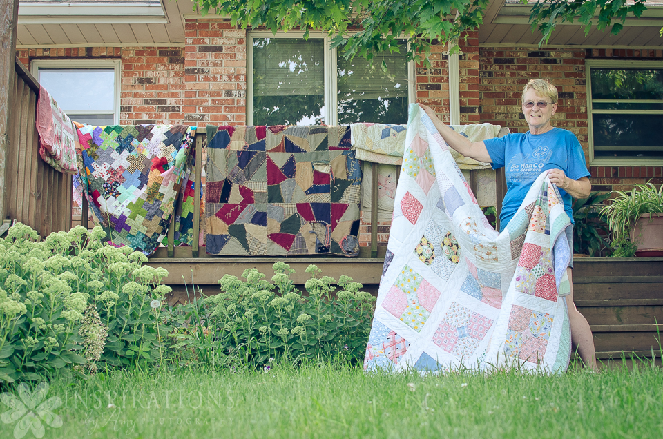 Woman hanging quilts on a railing outside a house