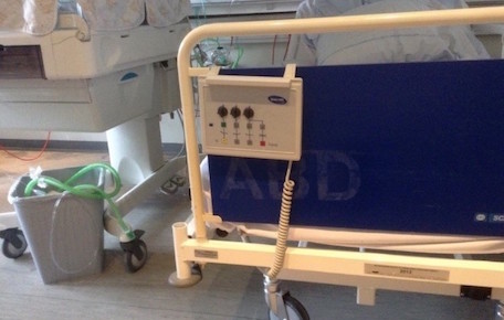 An infant bed and a parent bed in the Danish neonatal ward. The clear, window-transparent infant bed or incubator is covered with baby blankets to darken the baby's space