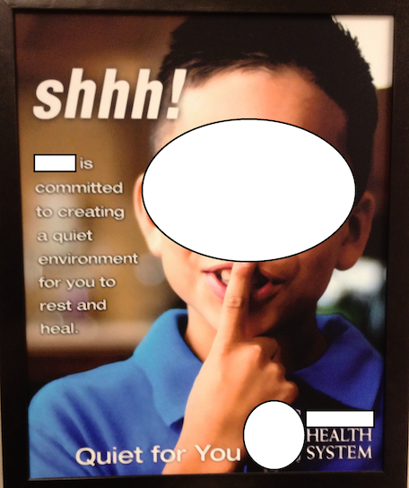 A large poster with a photo of a young boy with one finger to his lips gesturing shhh. Identifying marks (names, faces) are blurred out. Text on the poster reads: Shhh! (NICU name) is committed to creating a quiet environment for you to rest and heal.