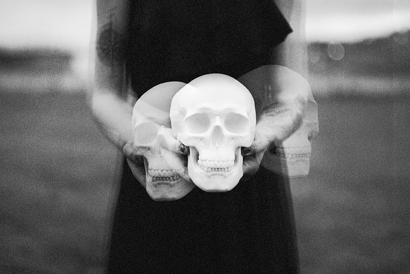 black and white image of woman in black dress holding a skull