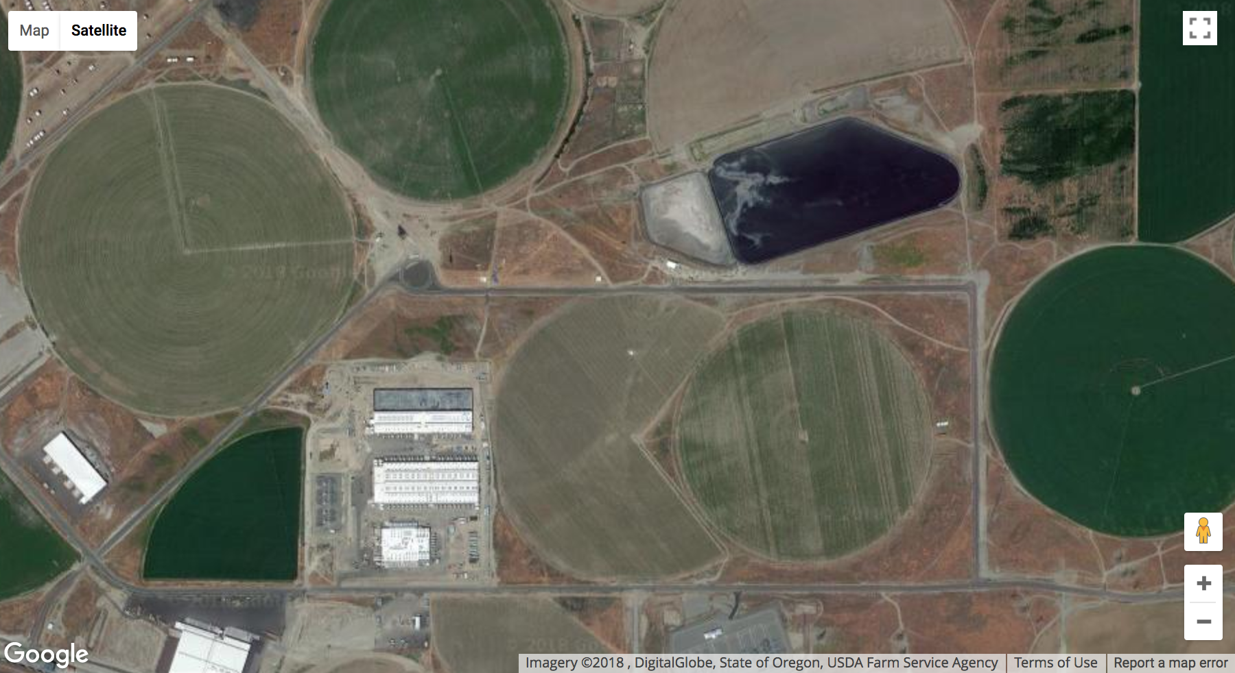 a Google Maps satellite shot of a low concrete building surrounded by agricultural fields
