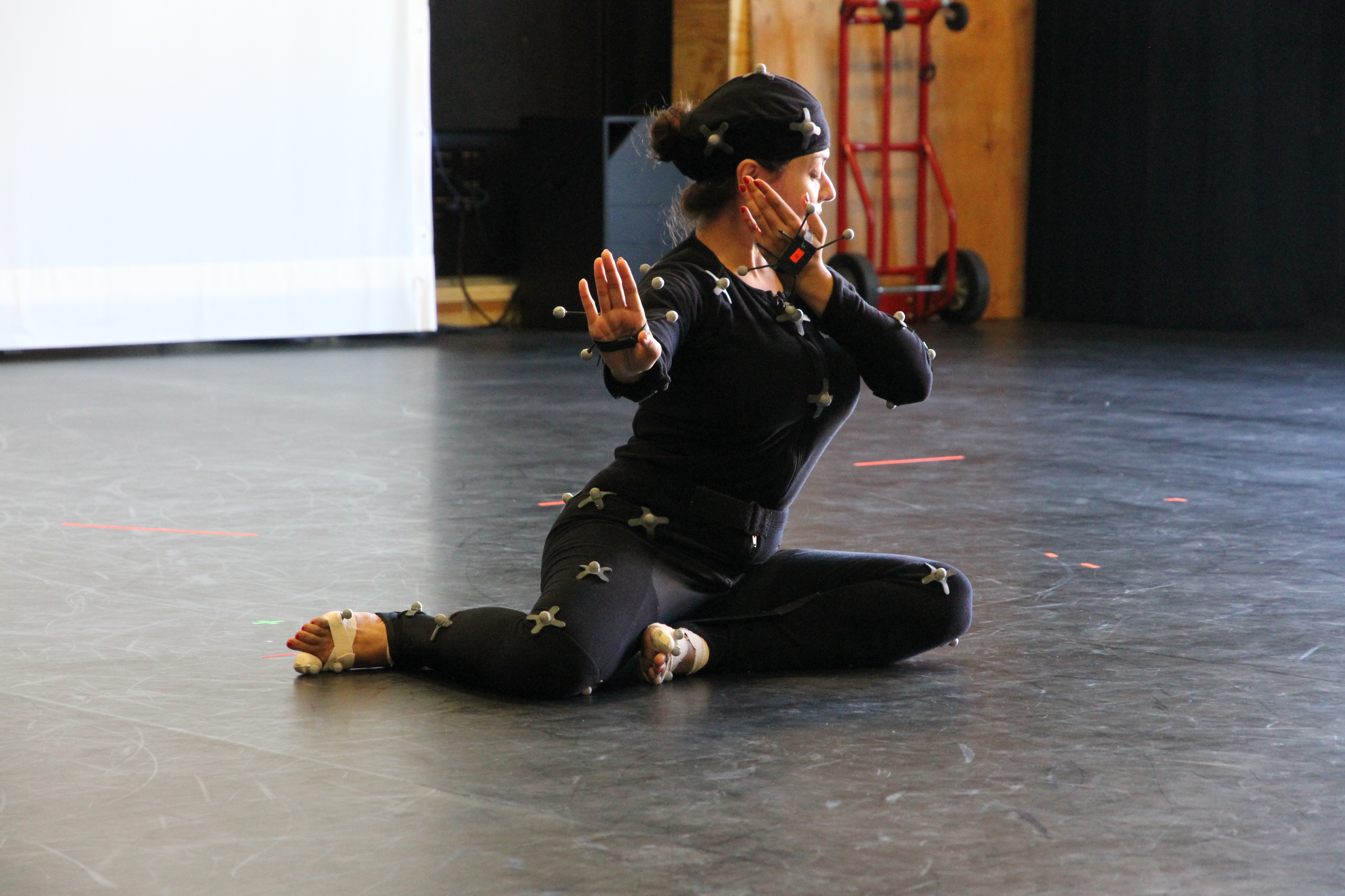 woman in black seated on floor in dancing pose