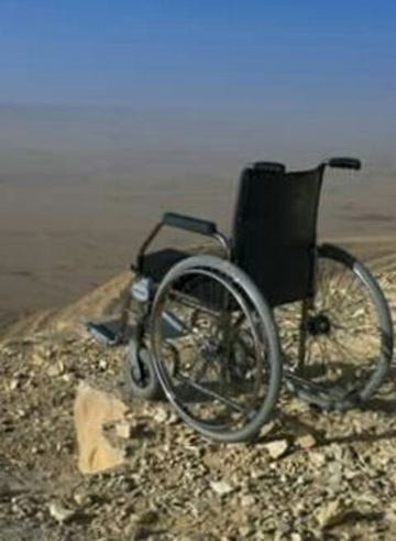 An image shows an empty wheelchair standing on the edge of an outlook.