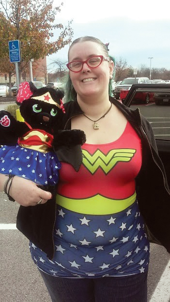 A photo shows a woman who is wearing the Superman logo while holding a stuffed animal in a matching outfit.