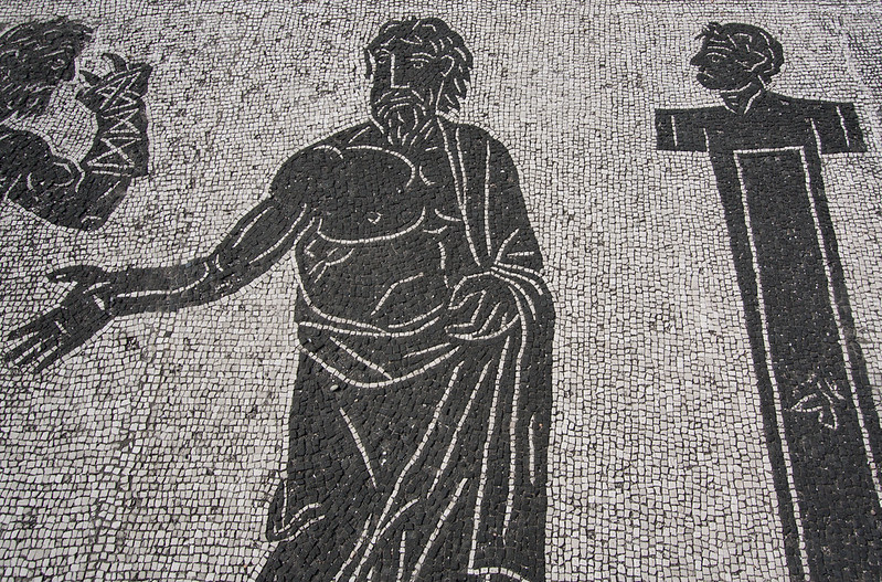 a black and white bath house mosaic in Ostia Antica, representing three men