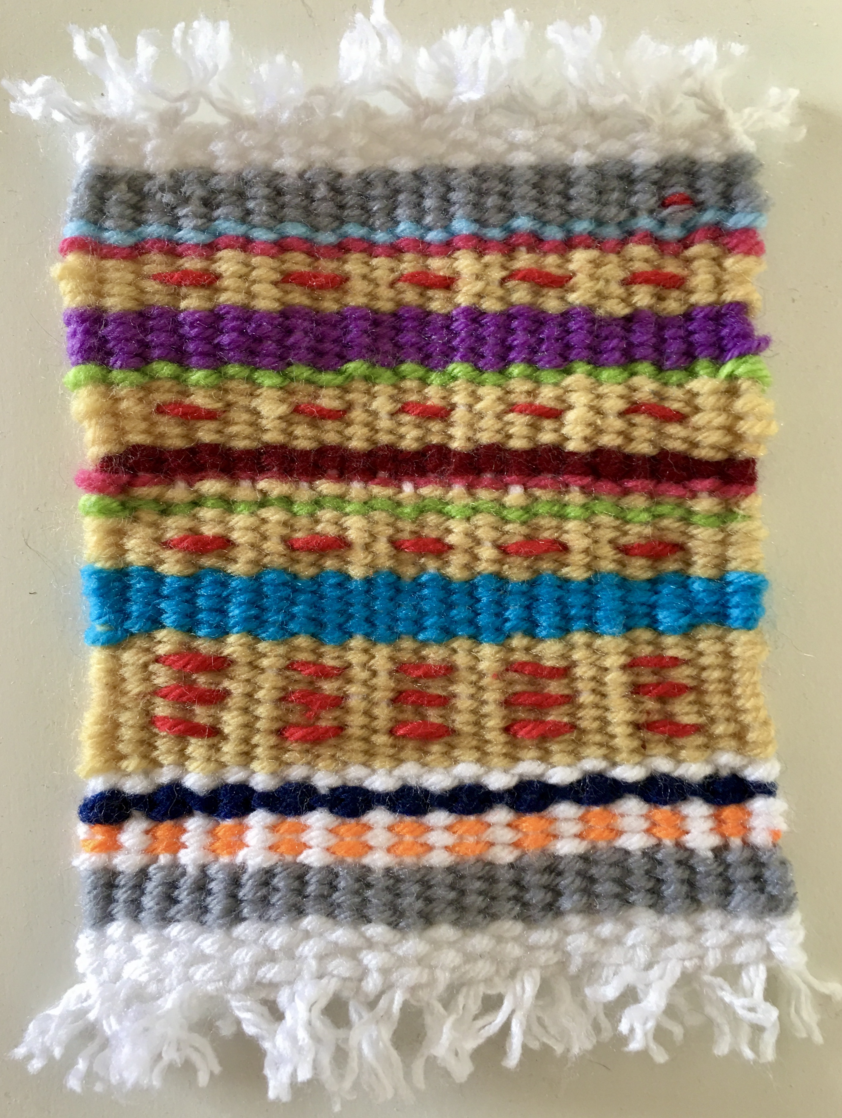 a small rectangular weaving with stripes of irregularly patterned colors