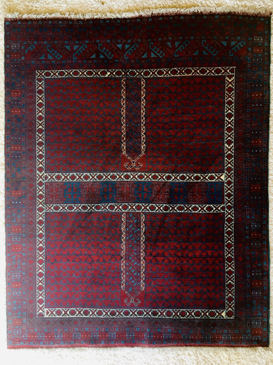 A red, blue, and white rug featuring multiple intricate patterns