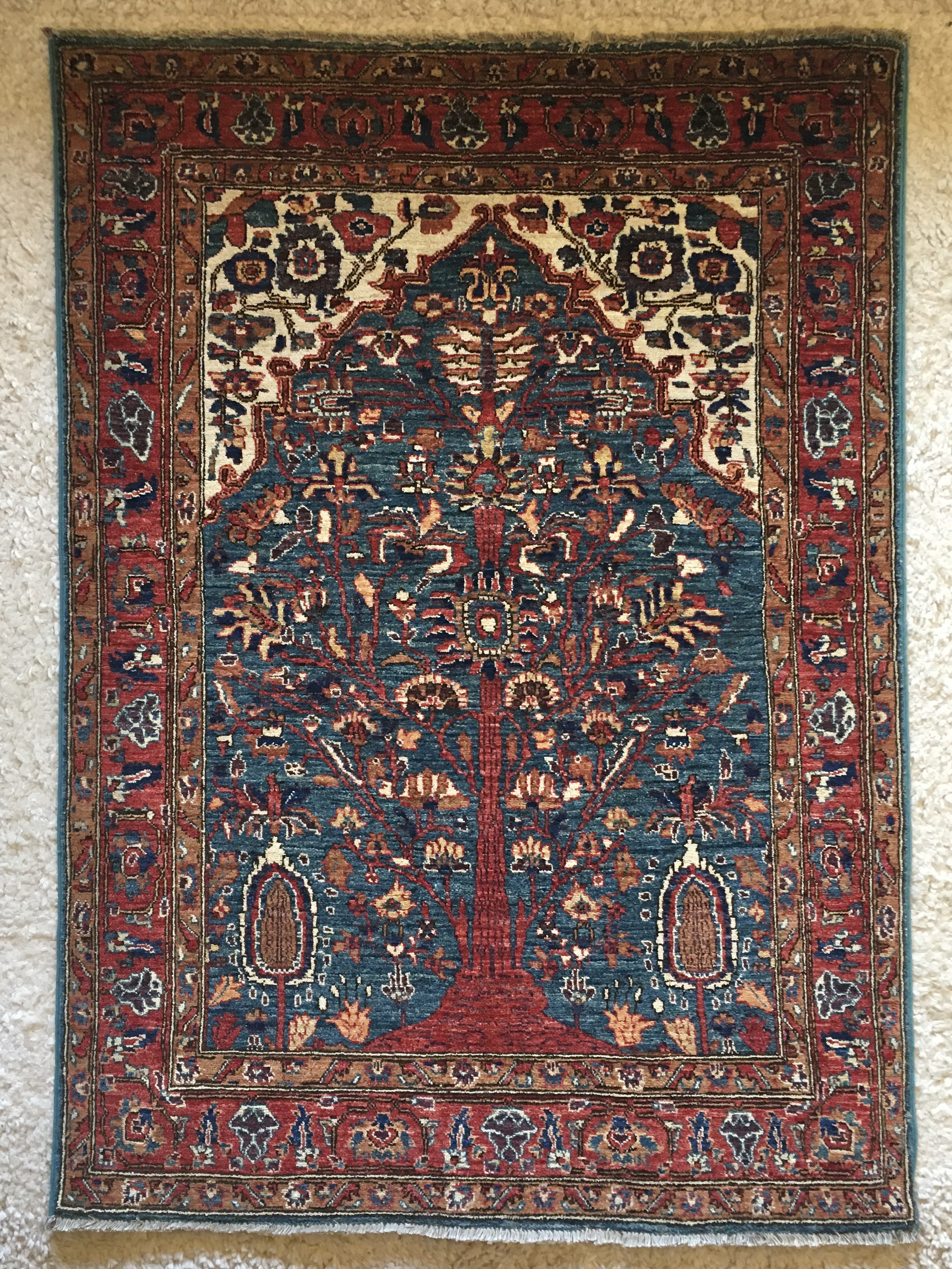 a red and blue rug depicting the tree of life