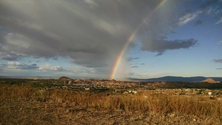dramatic landscape photo of a rainbow arcing over the resevoirs near the EARU-Prescott campus.