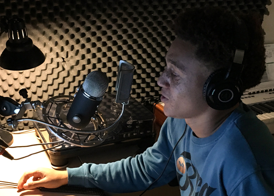 Student speaking into a microphone in the audio suite
