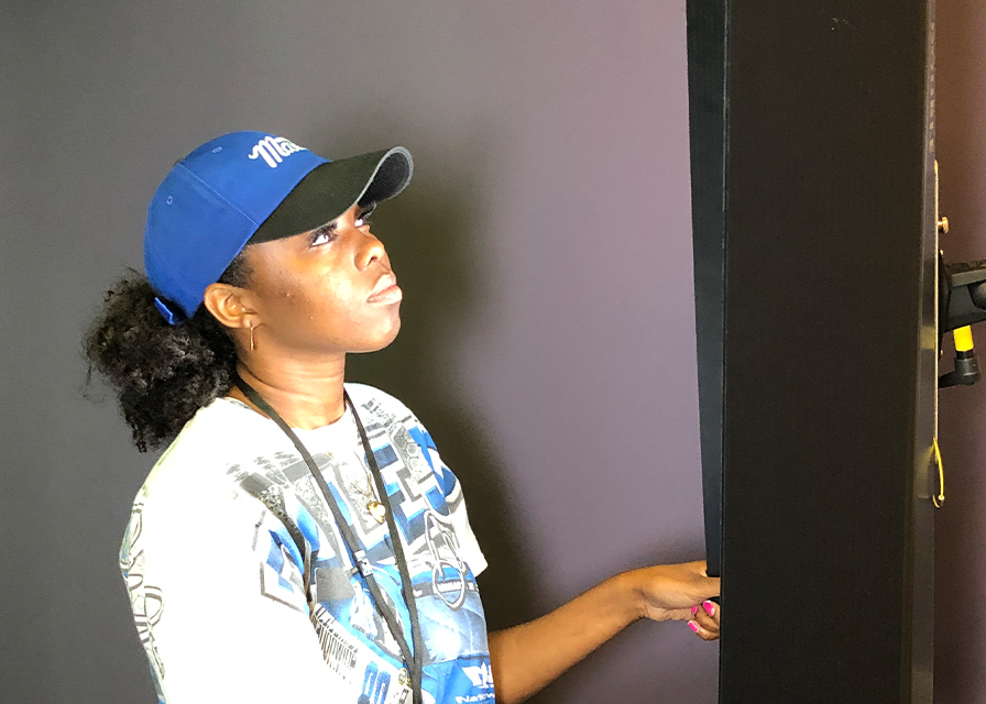 Student wearing blue hat looking at a screen in the video/photography suite