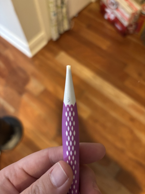 A broken plastic crochet hook with a magenta handle.
