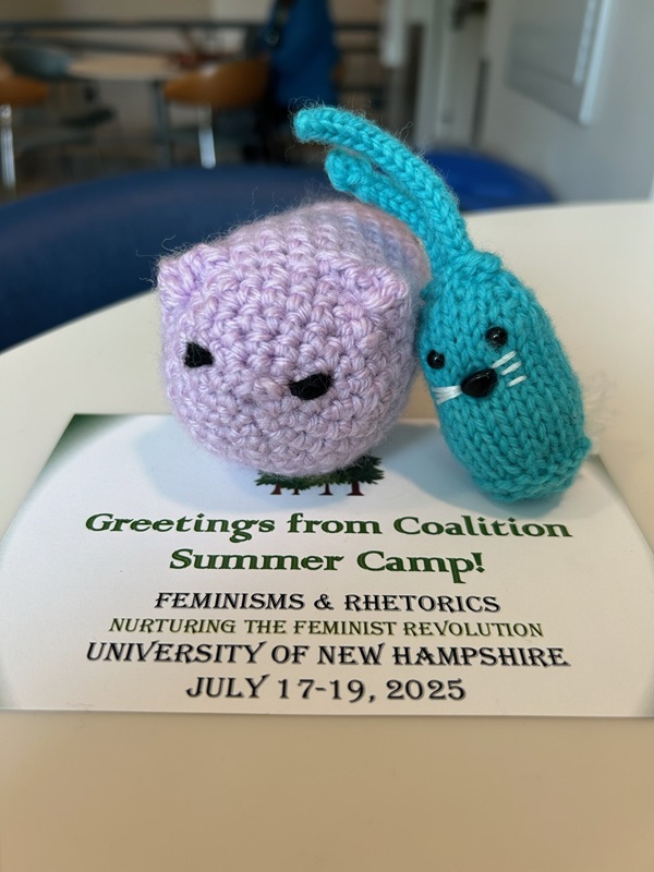 CC and a purple cat creature friend pose on top of a FemRhet postcard.