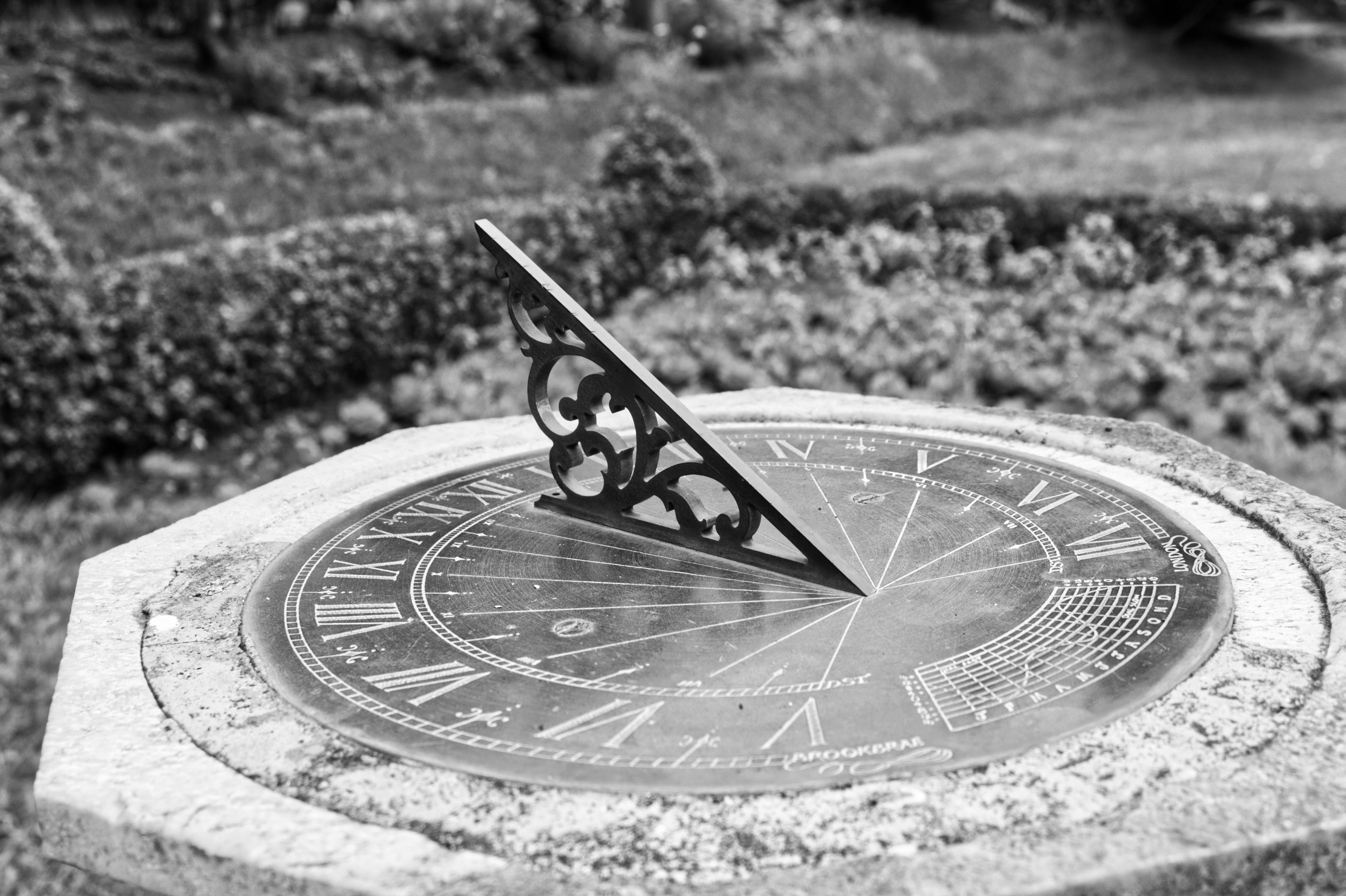 A grey-scale sundial sitting atop a stone slab.