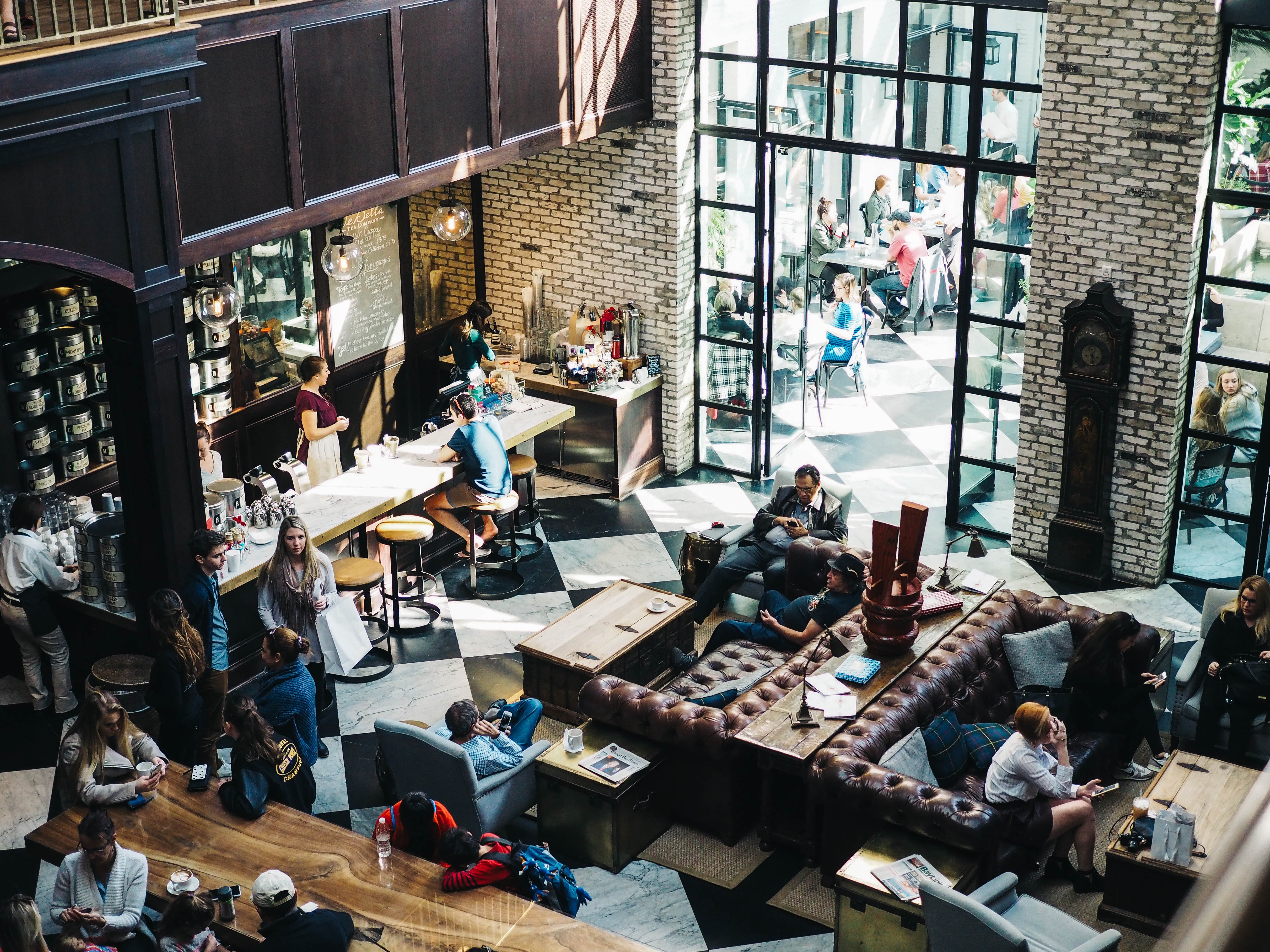 A busy coffee shop with people all around. Some people are on phones and some are on laptops.