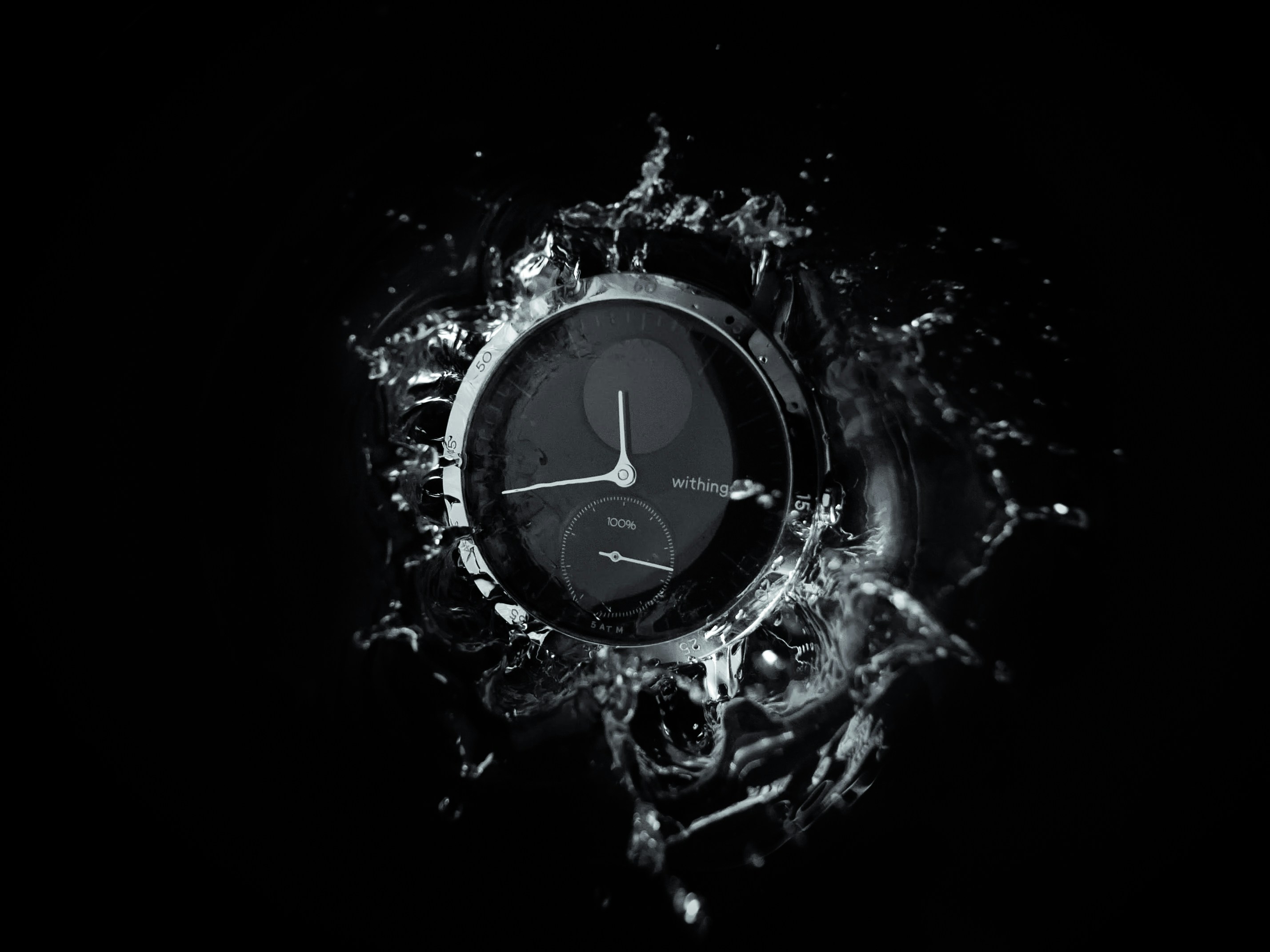 A watchface splashing into a black body of water.