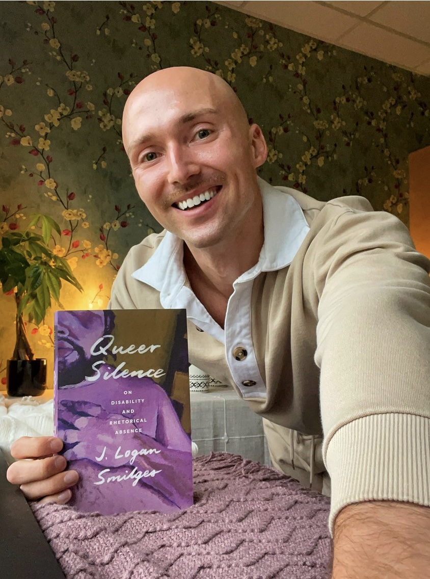 Dr. Smilges holding their book, Queer Silence