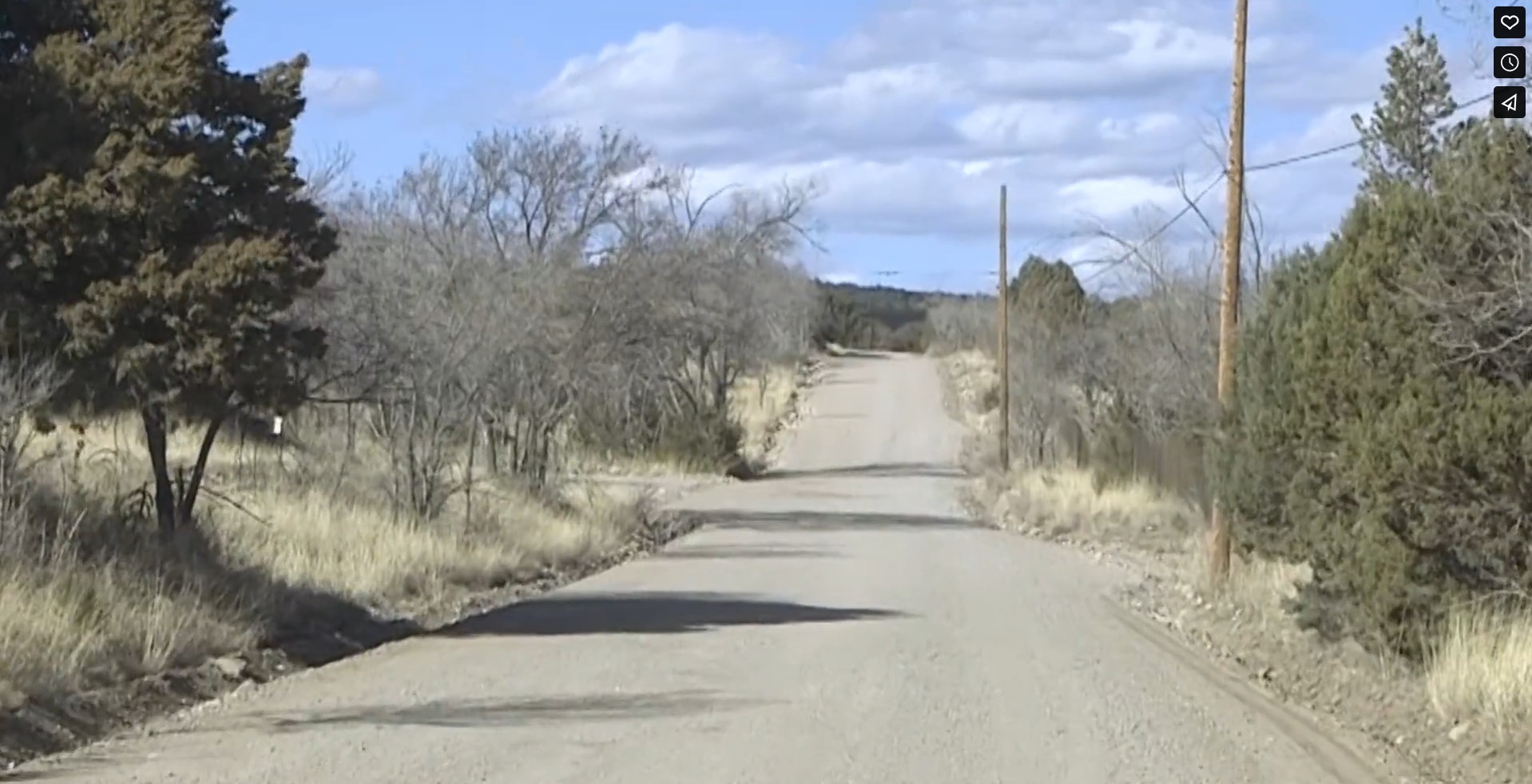 Screenshot at 0:03. Image shows a gravel road in the country. There is desert fauna on both sides of the road