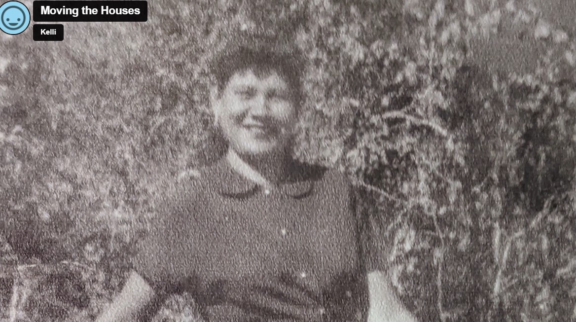 Screenshot at 7:29. Image shows a black and white photo of a smiling woman standing in front of some trees
