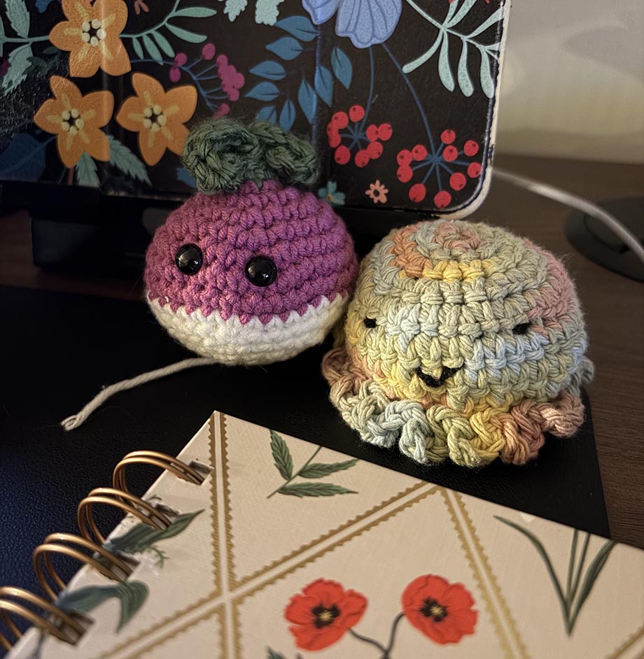 Two colorful crocheted Conference Creatures on Erin's desk (radish and rainbow jellyfish).