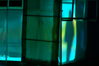Image of green film frame cast against the side of the CompuObscura, revealing shadows of participants inside the device. Taken by Cal Poly Architecture class students using class-created model and slide projector, Spring 2004.