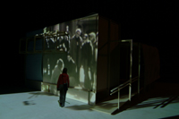 Image of old Lumiere film (crowd scene) displayed on the CompuObscura while potential visitor passes by. Taken by Cal Poly Architecture class students using class-created model and slide projector, Spring 2004. 