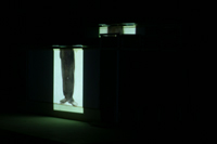 Image of Charlie Chaplin just from legs down, projected on side of CompuObscura building model. Taken by Cal Poly Architecture class students using class-created model and slide projector, Spring 2004.